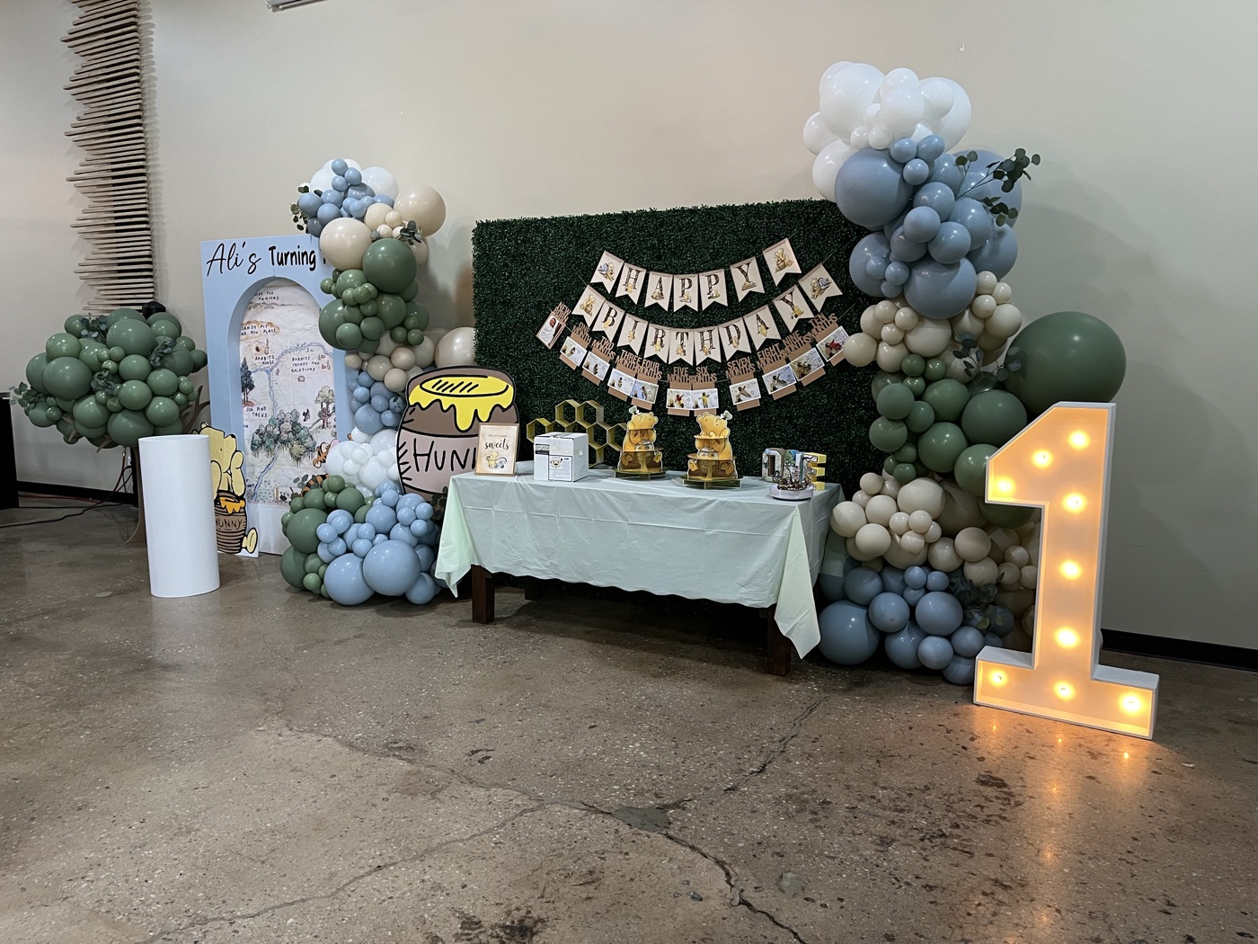 A woodland-themed birthday display with balloons and a marquee number one